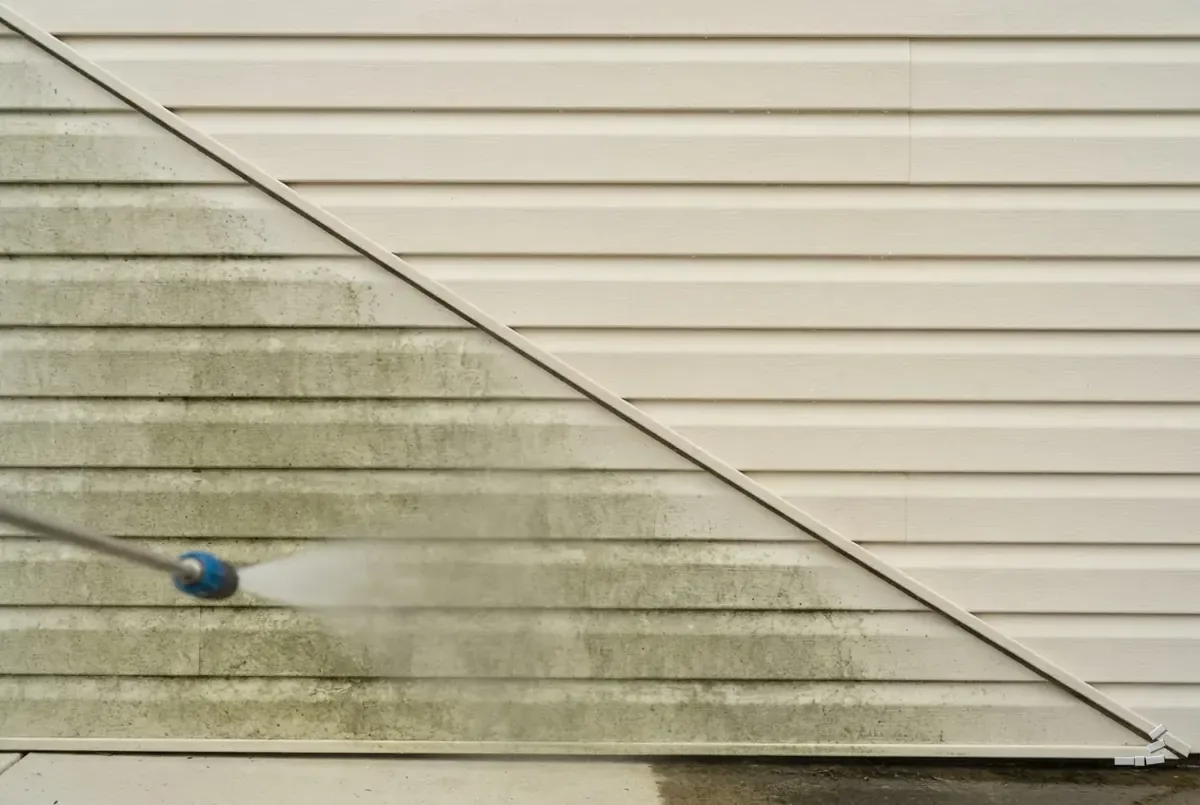 Photograph-style vinyl siding half cleaned along a diagonal — close detail