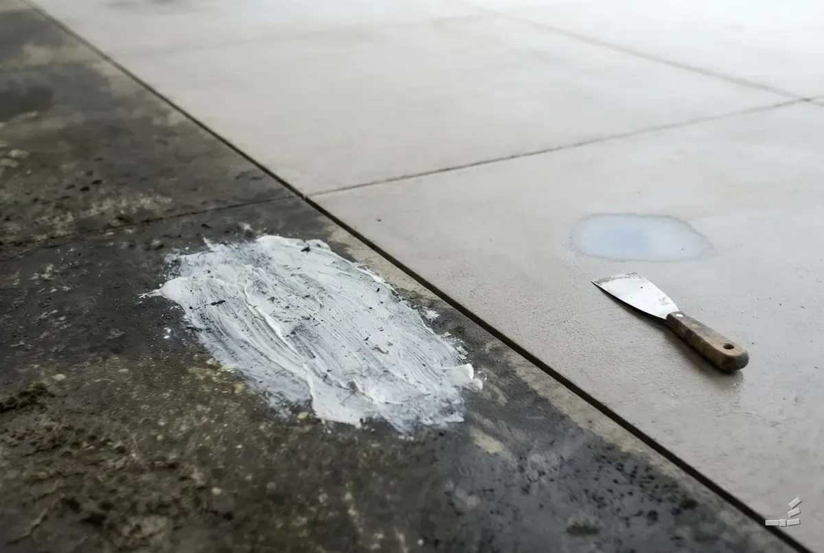 Photograph-style garage floor with an oil stain on the uncleaned half — close detail