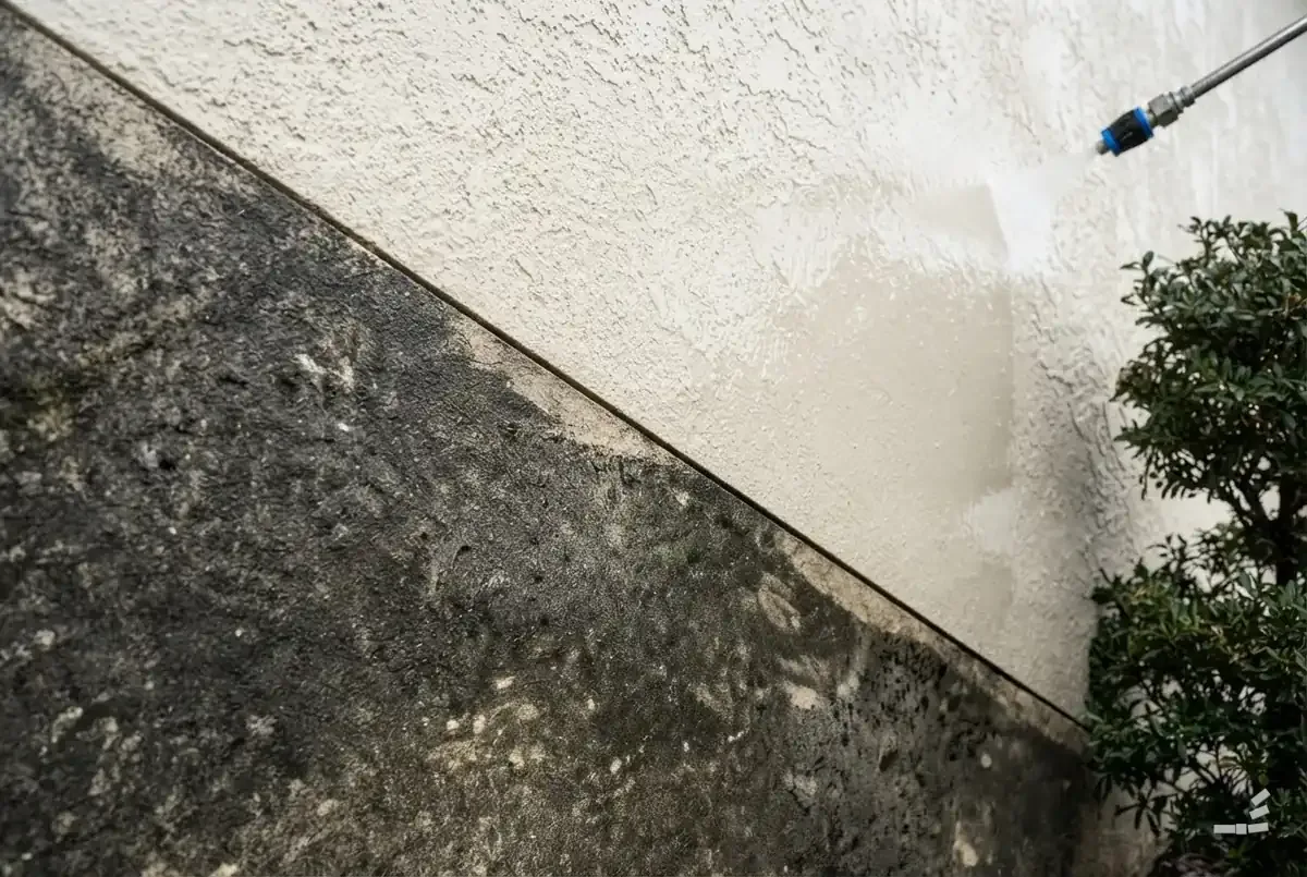 Photograph-style stucco wall half cleaned along a diagonal — close detail